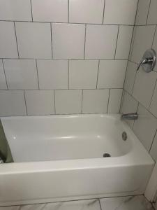 a white bath tub in a bathroom with white tiles at Nitey Nite Motel in South Windsor