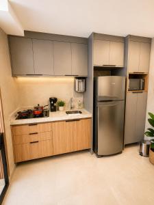 a kitchen with a stainless steel refrigerator and wooden cabinets at Alugueasy - EASY Noroeste in Brasília