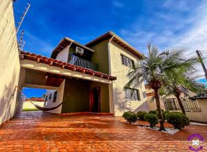 a house with a palm tree in front of it at Casa Shanti - conforto e tranquilidade. in Dourados