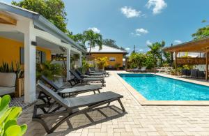 a pool with lounge chairs next to a house at J&L Resort in Willemstad