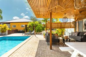 an outdoor patio with a pool and a wooden pergola at J&L Resort in Willemstad