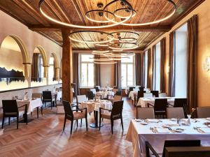 un ristorante con tavoli, sedie e lampadario a braccio di Steigenberger Icon Grandhotel Belvédère a Davos