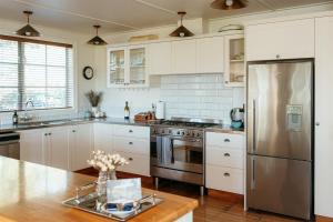 a kitchen with white cabinets and a stainless steel refrigerator at Aldourie Lodge - Lake Tekapo in Lake Tekapo