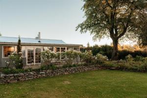 a house with a stone wall in front of a yard at Aldourie Lodge - Lake Tekapo in Lake Tekapo