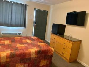 a bedroom with a bed and a dresser with a television at Nitey Nite Motel in South Windsor