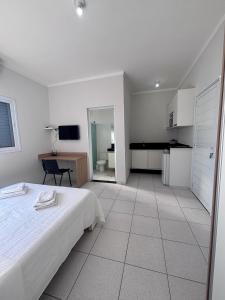 a white bedroom with a bed and a desk at Spazio Italian Lofts in Paulínia