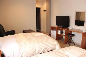 a hotel room with a bed and a desk with a television at セントロ大隅ホテルオオサキ in Kanoya