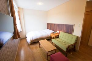 a bedroom with a bed and a couch and a table at セントロ大隅ホテルオオサキ in Kanoya +15 photos