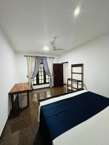 a bedroom with a bed and a desk and a window at Ceylon Mist Villa in Narandanda