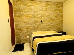 two beds in a room with a brick wall at Tiny House, Refúgio Aconchegante em Mucugê in Mucugê