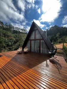 eine große Holzterrasse mit Stühlen und ein Gebäude in der Unterkunft Cabanas do vale in Itaquá