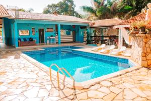 a swimming pool with chairs and a house at Pousada Vilarejo de Minas in Itapeva