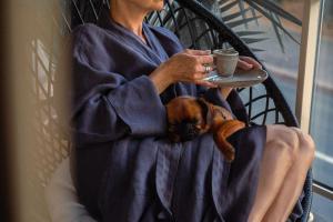 Eine Frau mit einem Hund und einer Tasse Kaffee in der Unterkunft Unique Boutique Hotel Antibes Juan-les-Pins in Juan-les-Pins