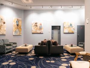 a waiting room with a couch and chairs and paintings at Sofitel Gold Coast Broadbeach in Gold Coast