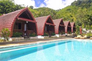 a row of huts next to a swimming pool at Dudu Cottage Nusa Penida in Nusa Penida