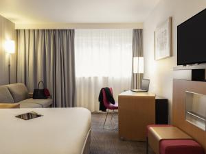 a hotel room with a bed and a couch at Novotel Roissy Saint Witz in Saint-Witz