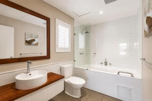 a bathroom with a sink and a toilet and a tub at Caves House Apartments Yallingup in Yallingup