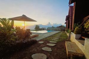 a swimming pool with an umbrella next to a house at Dudu Cottage Nusa Penida in Nusa Penida