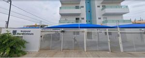 a fence with a blue umbrella in front of a building at Apartamento Novo e ventilado in Petrolina +8 photos