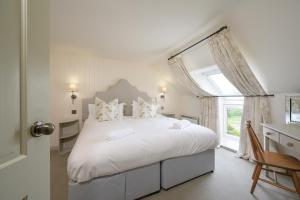 a white bedroom with a large bed and a window at Cardross Holiday Cottages in Arnprior