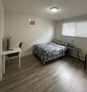 a bedroom with a bed and a desk with a computer at Ron's Place in Saskatoon