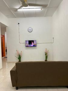 a couch in a room with a clock on a wall at Bertam Transit Homestay in Kampong Alor