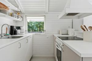 a white kitchen with a sink and a window at Experience Nature's Embrace And Peace in Græsted