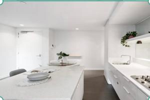 a white kitchen with a counter and a sink at City Vibe on Dorcas Southbank in Melbourne