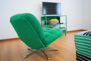 a green chair in a living room with a television at Horta Joy! in Horta