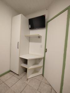 a room with a white closet with a tv on the wall at Casa Almendra in Búzios