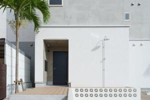 a white building with a blue door and a palm tree at Solis Studio Miyako SeaSide in Miyako-jima