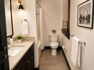 a white bathroom with a toilet and a sink at Brick & Bed Riverfront Lofts, T 303 in Saint Louis