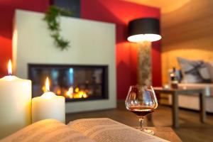 un livre ouvert et un verre de vin sur une table avec des bougies dans l'établissement Hotel Regglbergerhof, à Nova Ponente