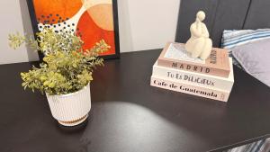a table with a stack of books and a vase with flowers at LOFT 02 · Loft127-02 Compacto, equipado, ótima localização in Itajaí