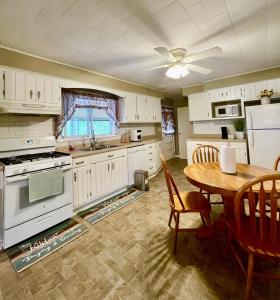 a kitchen with white cabinets and a table and a dining room at Xuan Pine House in Altoona