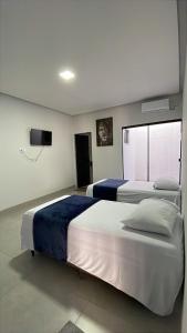 a bedroom with two beds and a flat screen tv at Hotel Iluminar in Goianésia