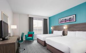 a hotel room with two beds and a television at Leonardo Hotel Cheltenham in Cheltenham
