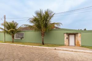 a green building with two palm trees in front of it at Casa de praia Peruibe in Peruíbe