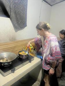a woman standing in a kitchen preparing food at Beda gaya ecolodge Rangsot 1 in Tanjung