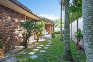 a garden with trees and a brick building at Bromeliads in Iluka