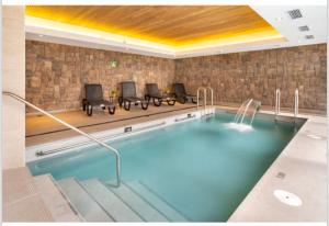 a large swimming pool with chairs in a room at Depto con Piscina Temperada 2D y 2B in Puerto Varas
