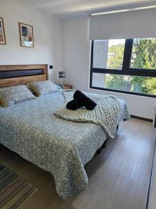 a bedroom with a bed with a blanket and a window at Depto con Piscina Temperada 2D y 2B in Puerto Varas