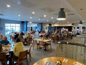 a group of people sitting at tables in a restaurant at Dollys Den in Pagham