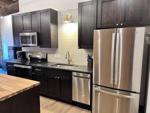 a kitchen with a stainless steel refrigerator and black cabinets at Brick & Bed Riverfront Lofts, T 308 in Saint Louis +7 photos
