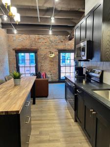 a kitchen with black cabinets and a living room at Brick & Bed Riverfront Lofts, T 308 in Saint Louis