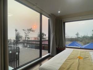 a bedroom with a large window with a bed and a balcony at Châu Anh House in Ðố Sơn