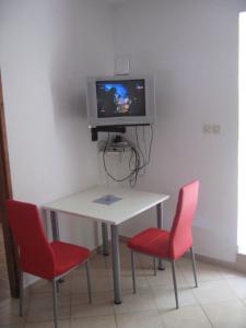 a table with two chairs and a tv on a wall at Nevera Apartments Pašman,Banj in Banj