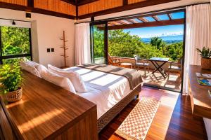 a bedroom with a bed and a large window at Pousada Rosa Norte in Praia do Rosa +172 photos