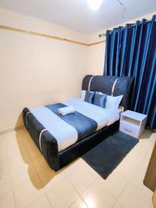 a bed in a room with blue curtains at 1 Bedroom in Section 58 behind Kunste Hotel in Nakuru
