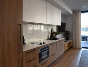 a kitchen with white cabinets and a stove top oven at Kove Apartment - G03 in Kiama